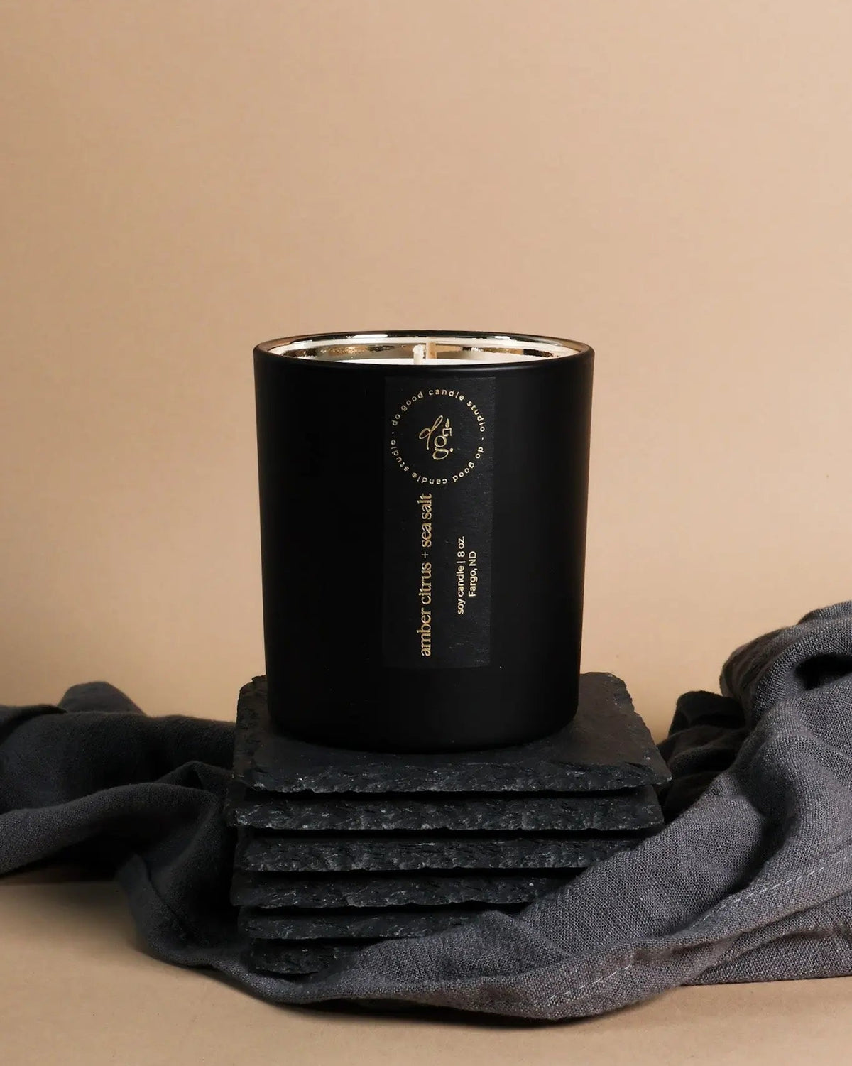 soy candle in matte black vessel with a label on a beige background