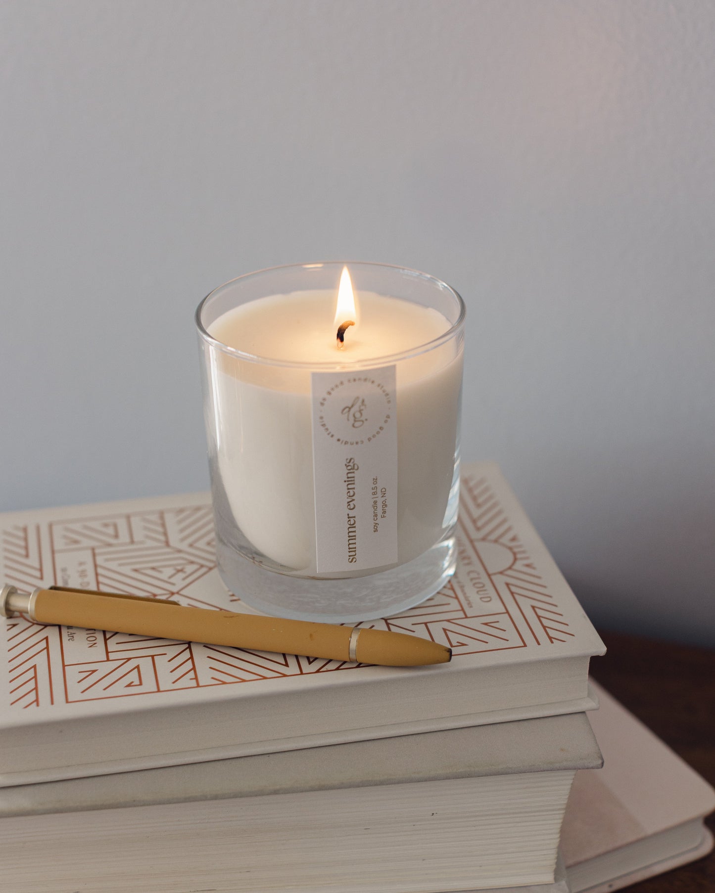 Summer Evenings candle burnng on a stack of books with a pen