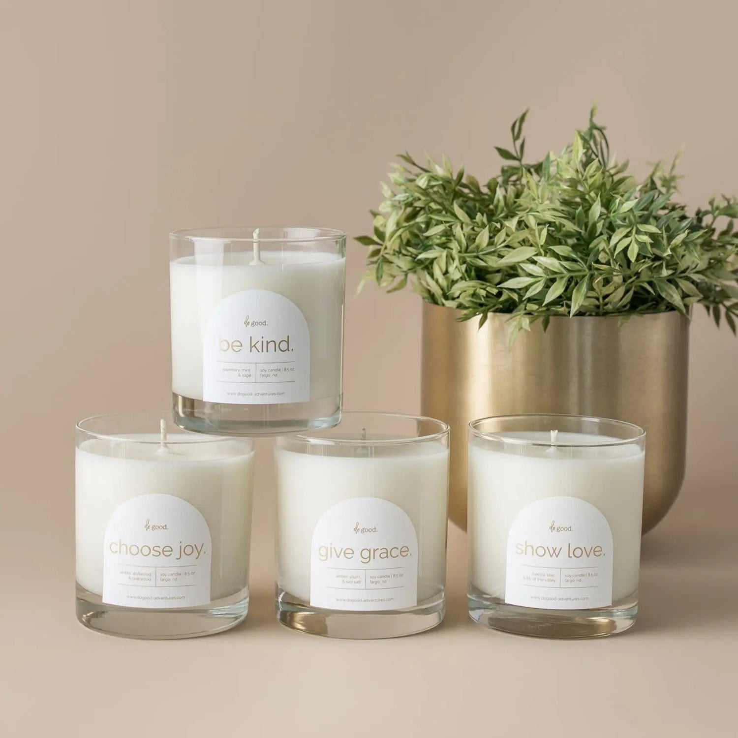 Do Good Collection of four candles on a beige background with a gold pot with greens inside of it