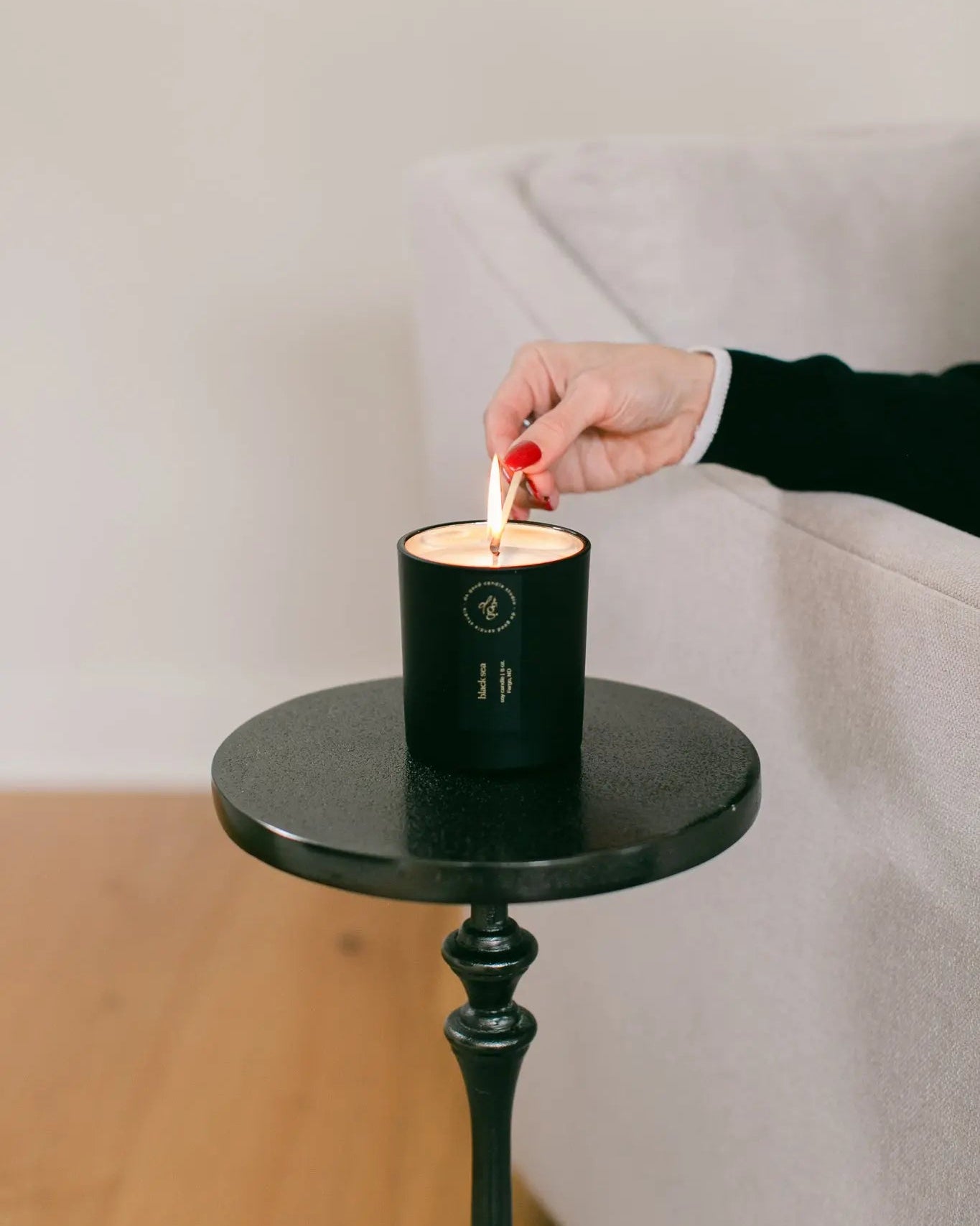Person lighting a candle on a small round table with a plain background