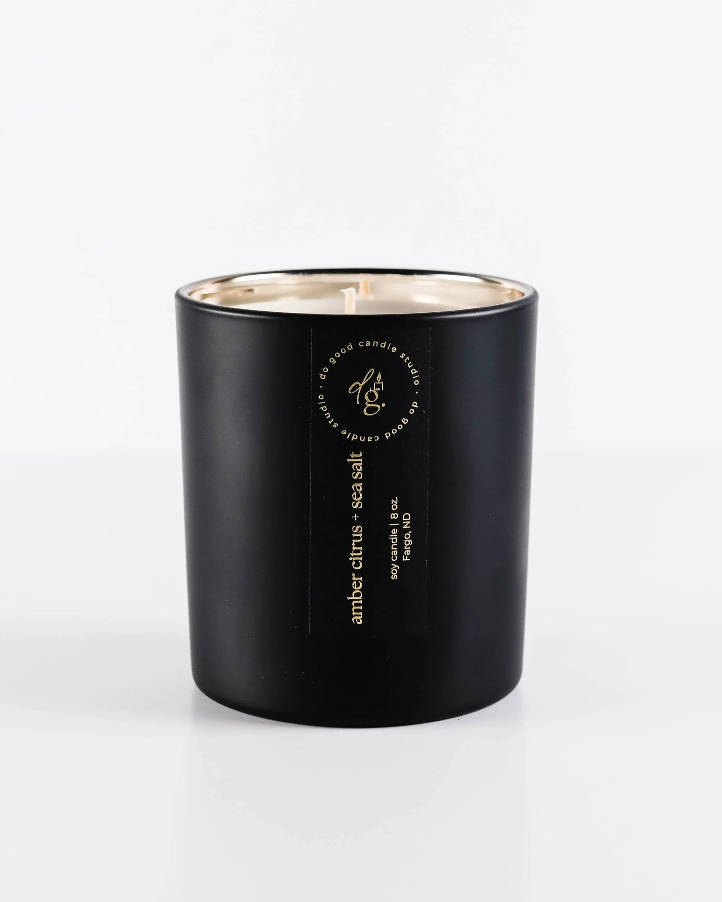 soy candle in matte black vessel with gold interior on a white background