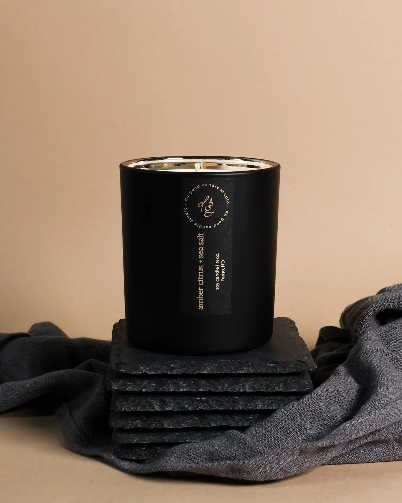 soy candle in matte black vessel with a label on a beige background
