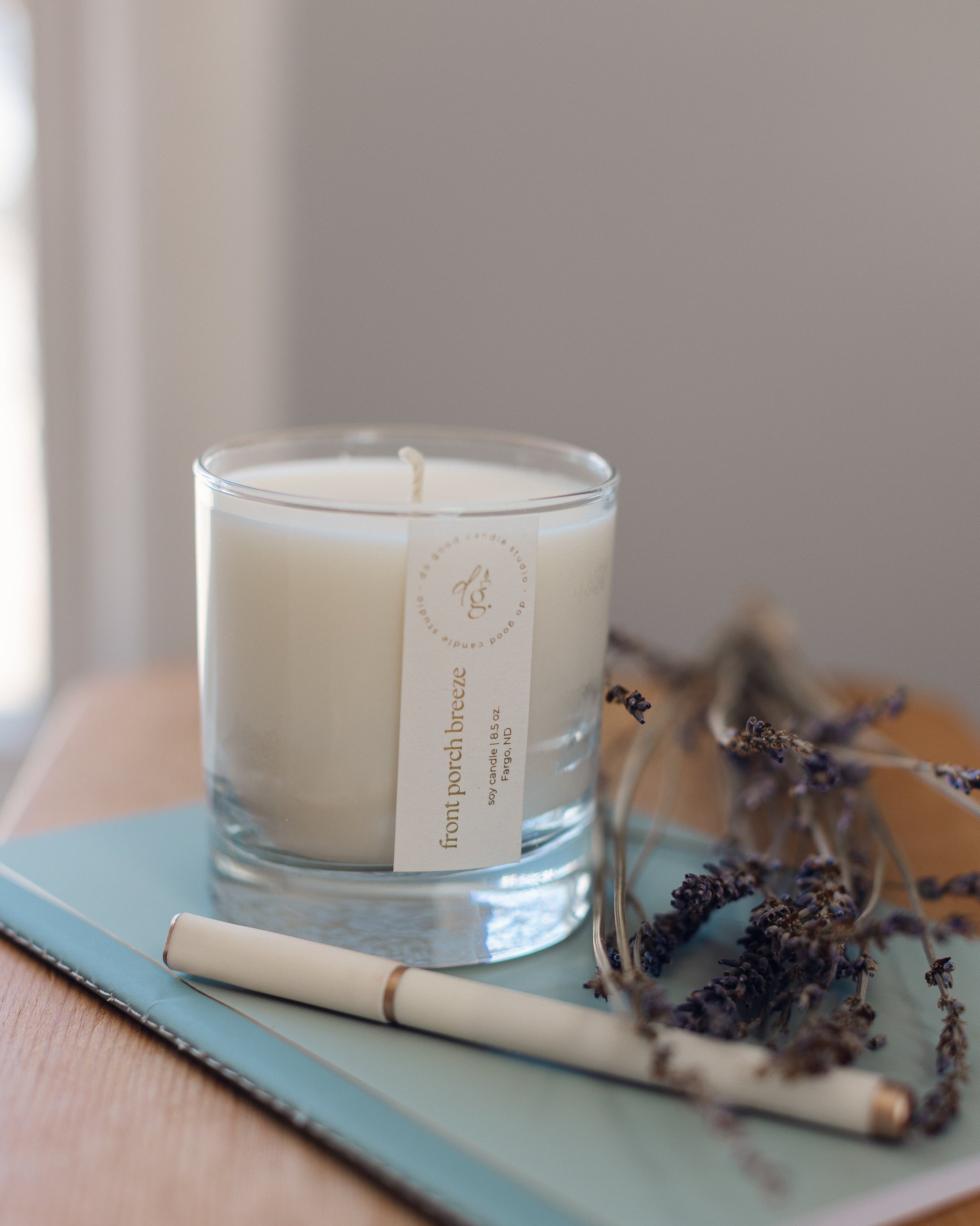 Front Porch Breeze candle styled on a journal with pen and lavender