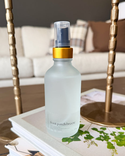 front porch breeze roon spray sitting on a book with a sofa in the background