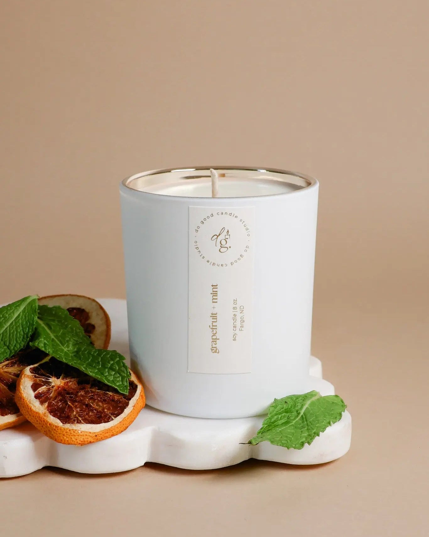 Grapefruit + Mint styled on a beige badkdrop with a white scallp tray, grapefruit slices, and jind leaves