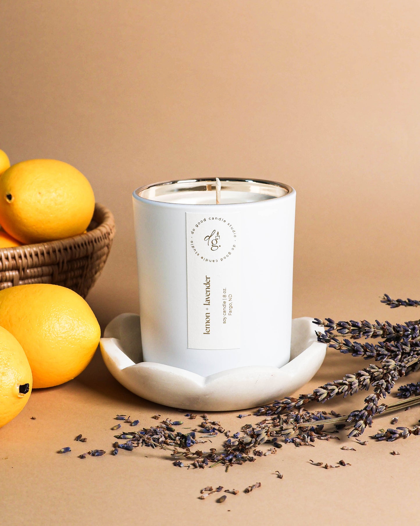 Lemon + Lavender andle styled on a beige backdrop with a bowl of lemons and sprig of lavender