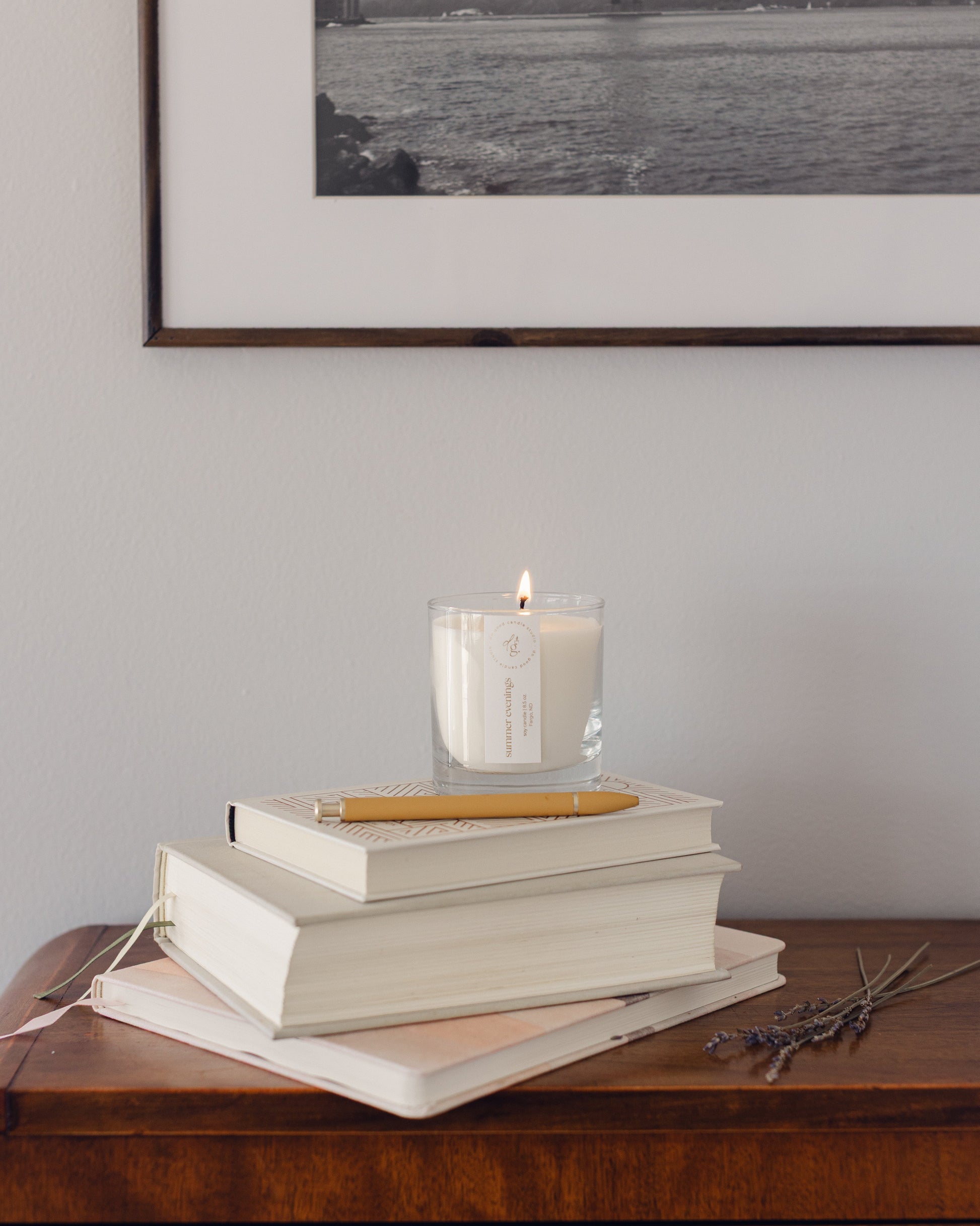 summer evenings candle burning on a stack of books on a console table