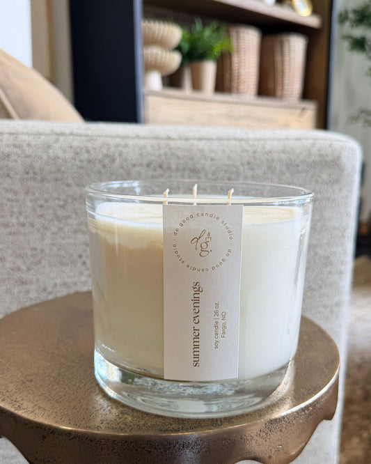 triple wick summer evenings candle on a table net to a chair
